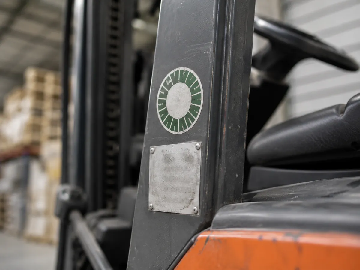 Nahaufnahme von Prüfplakette und Typenschild am Rahmen eines Gabelstaplers (mit KI erstellt)